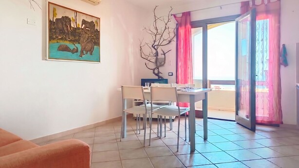 Ein Essbereich mit Tisch und Stühlen, einem Bild an der Wand und Blick durch eine Glastür.