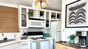 Una cocina moderna con armarios blancos, estufa, microondas y refrigerador.
