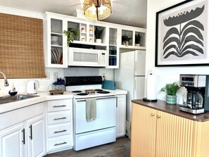 Une cuisine moderne avec des meubles blancs, une cuisinière, un four à micro-ondes et un réfrigérateur.
