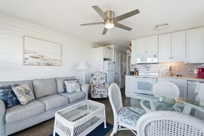 A modern living room with a grey sofa, a white wicker chair, and a glass table. - AR 308 Hilton Head Beach &Tennis Beach Lovers Only (Hilton Head Island)