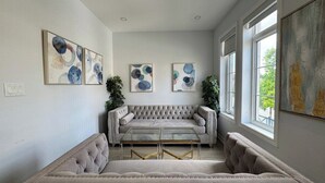 A room with a tufted sofa, a glass coffee table, and artwork on the walls. -     Oakville Executive Luxury Residence| 4BR • 7QB• 5 Ensuites • 2 Kitchens (Oakville)