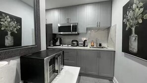 Una cocina moderna con electrodomésticos de acero inoxidable, gabinetes grises y obras de arte en las paredes.