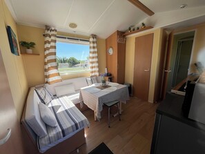 A compact room with a bed, a dining table, and a kitchenette. - Mobile Home in the Countryside (Juillac)