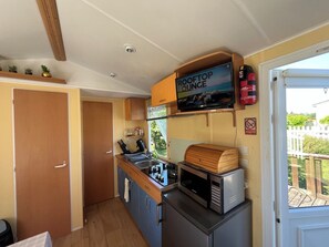 A compact kitchenette with a microwave, stove, and a sign indicating a rooftop lounge. - Mobile Home in the Countryside (Juillac)