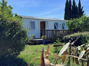 A single-story mobile home with a deck, surrounded by greenery and trees. - Mobile Home in the Countryside (Juillac)
