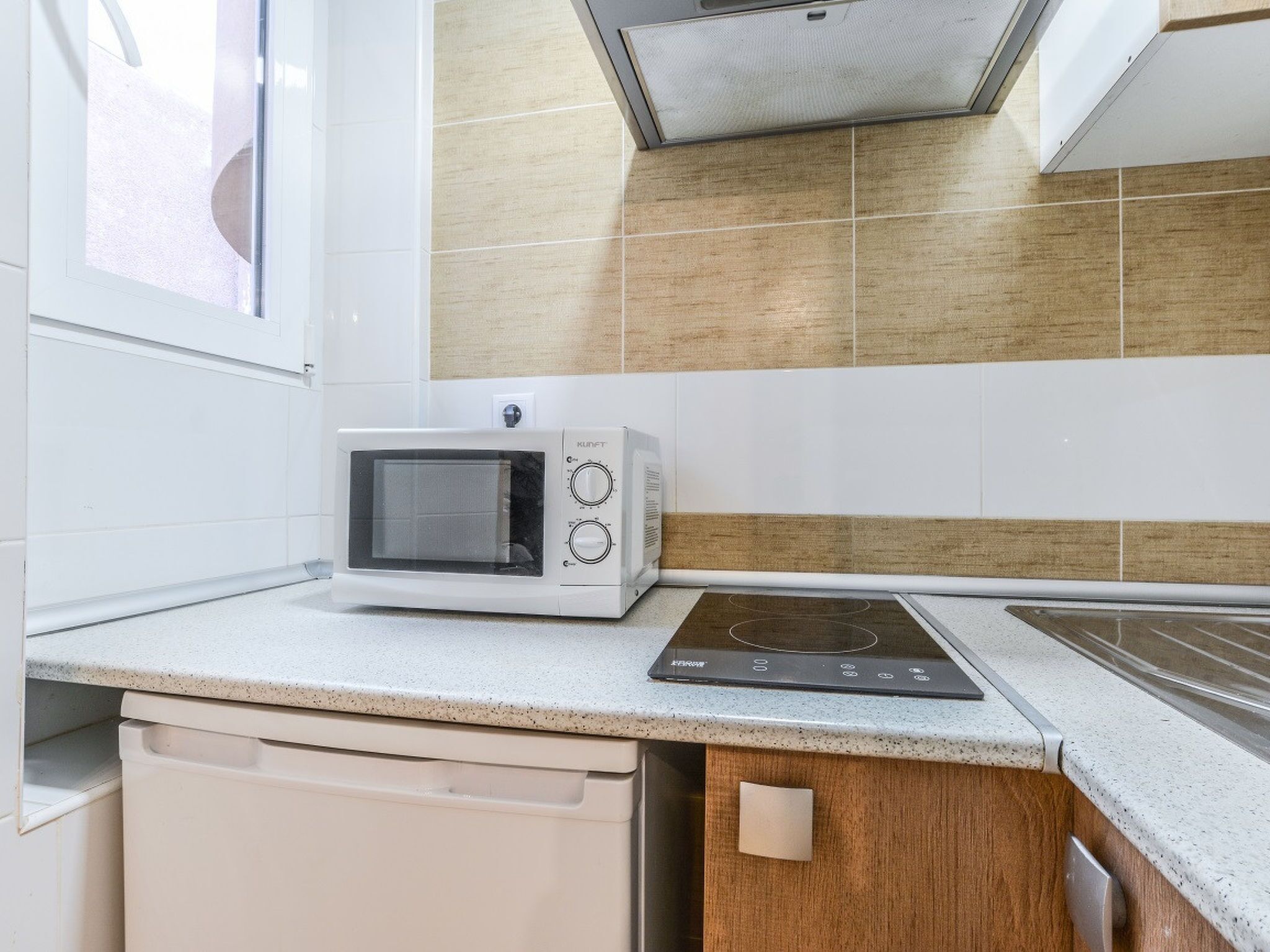 A kitchen with a microwave, induction cooktop, and a dishwasher.