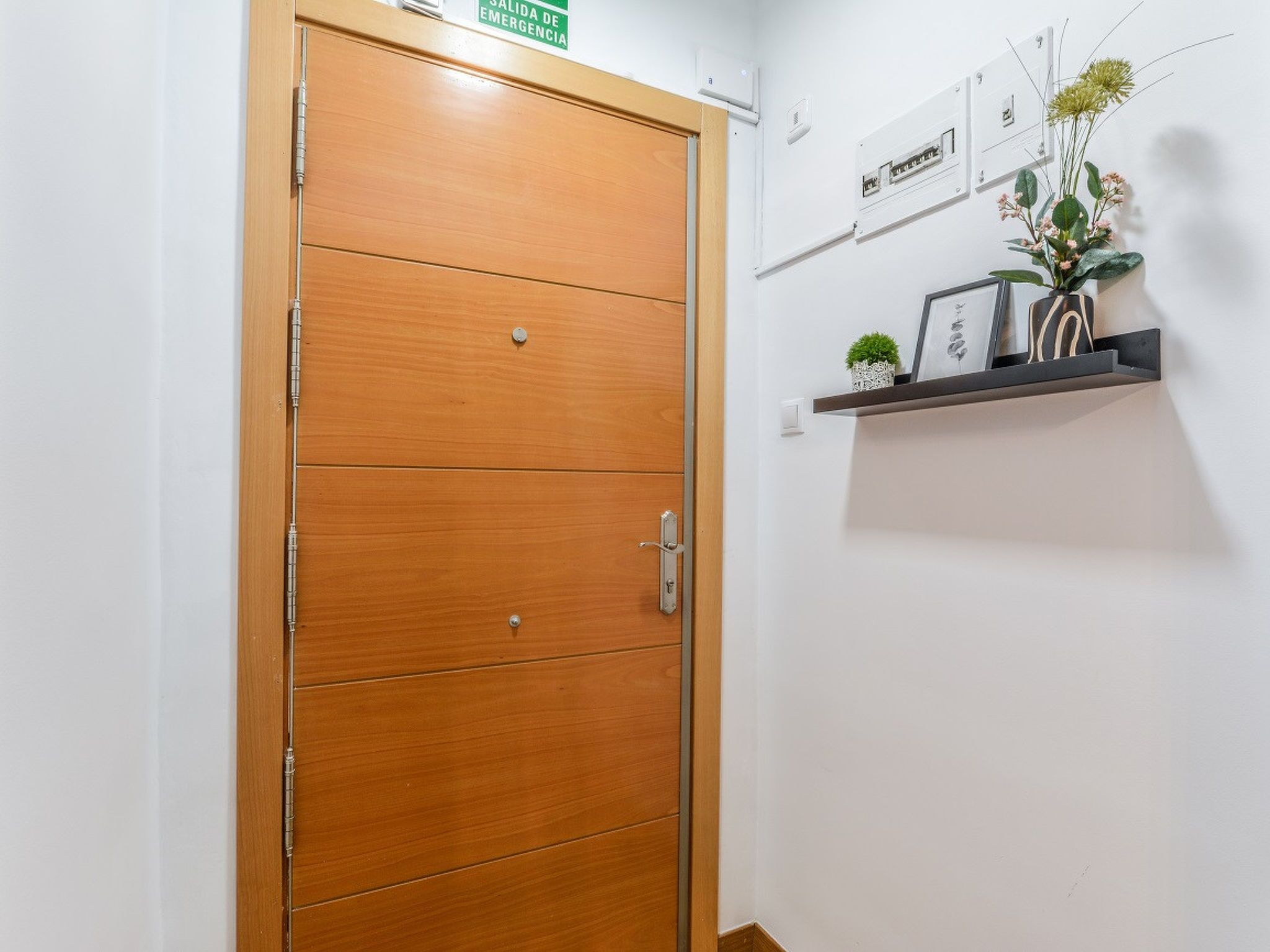 Una puerta de madera con un cartel encima, un estante con adornos y un enchufe.