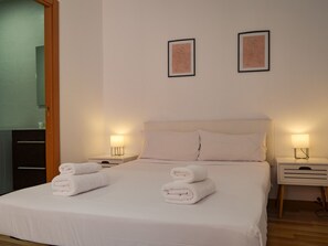 Ein Hotelzimmer mit einem Bett, zwei Nachttischlampen, einem Nachttisch und zwei gerahmten Kunstwerken an der Wand.