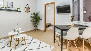 Moderni olohuone, jossa on ruokailutila, seinälle asennettu televisio ja suuri ikkuna.