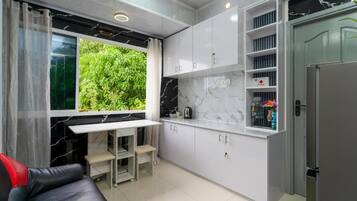 A compact kitchen with a built-in table, cabinets, and a refrigerator.