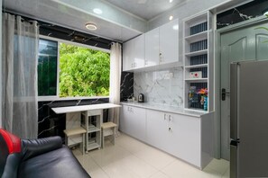 A compact kitchen with a built-in table, cabinets, and a refrigerator. - Naseema Hiya - Ukulhas Residences (Ukulhas)