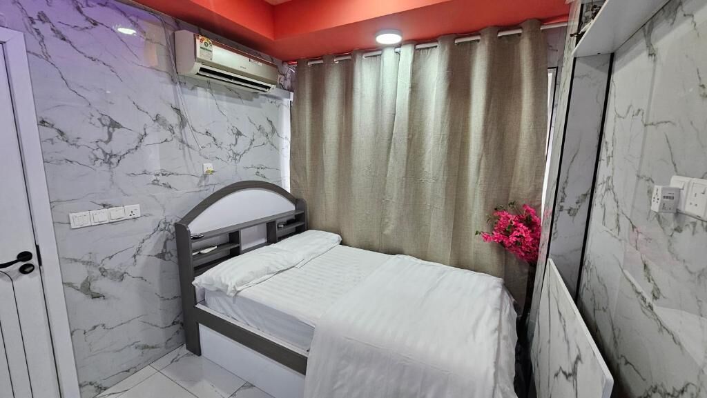 Un dormitorio con cama, ventana con cortinas y aire acondicionado de pared.