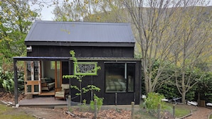 A modern house with a covered porch, a small garden, and a view of the surrounding trees.