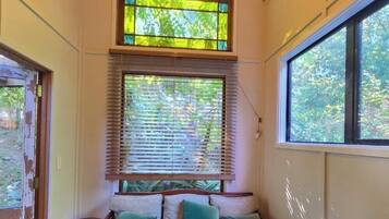 A room with a large window, a bench, and a view of greenery outside.