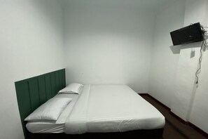 Una cama individual con cabecera verde en una habitación pequeña y poco iluminada.