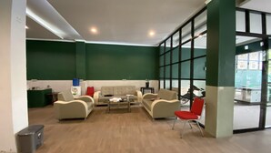 Een moderne zithoek met een bank, een bijzettafeltje en een rode fauteuil.