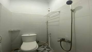 Un baño pequeño con inodoro, ducha y suelo de baldosas.