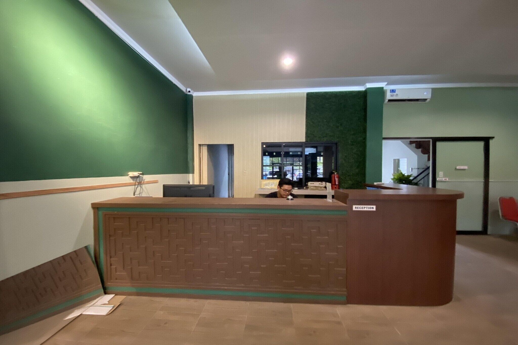 A reception desk with a green wall and a reception sign.