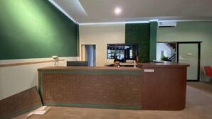 A reception desk with a green wall and a reception sign.