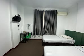 Habitación de hotel con dos camas, un escritorio con silla, televisor montado en la pared y una ventana con cortinas.