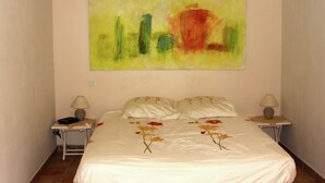 Een slaapkamer met een bed, twee nachtkastjes en een groot abstract schilderij aan de muur.
