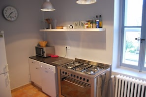 A compact kitchen with a microwave, stove, and dishwasher. There is a clock on the wall and a window with a view. - Estate with Shared Pool & Boules Court (Valréas)