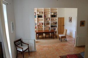 A dining area with a table and chairs, a bookshelf filled with books, and a radiator on the floor. - Fourteen-Person Valréas Holiday Home (Valréas)