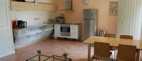 A compact kitchen with a dining area, a microwave, a stove, and a refrigerator.