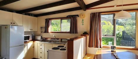 A compact kitchen with a refrigerator, microwave, stove, and wooden counter.