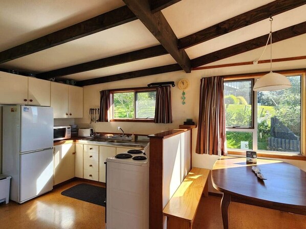 A compact kitchen with a refrigerator, microwave, stove, and wooden counter.