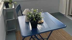A sunlit room with a table, chairs, potted plants, and a view through a window.
