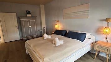 Ein Schlafzimmer mit einem großen Bett, zwei Nachttischlampen, einem Kleiderschrank und einer Tür.