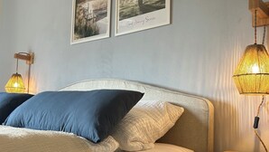 A bedroom with a bed, two wall-mounted lamps, and two framed pictures.