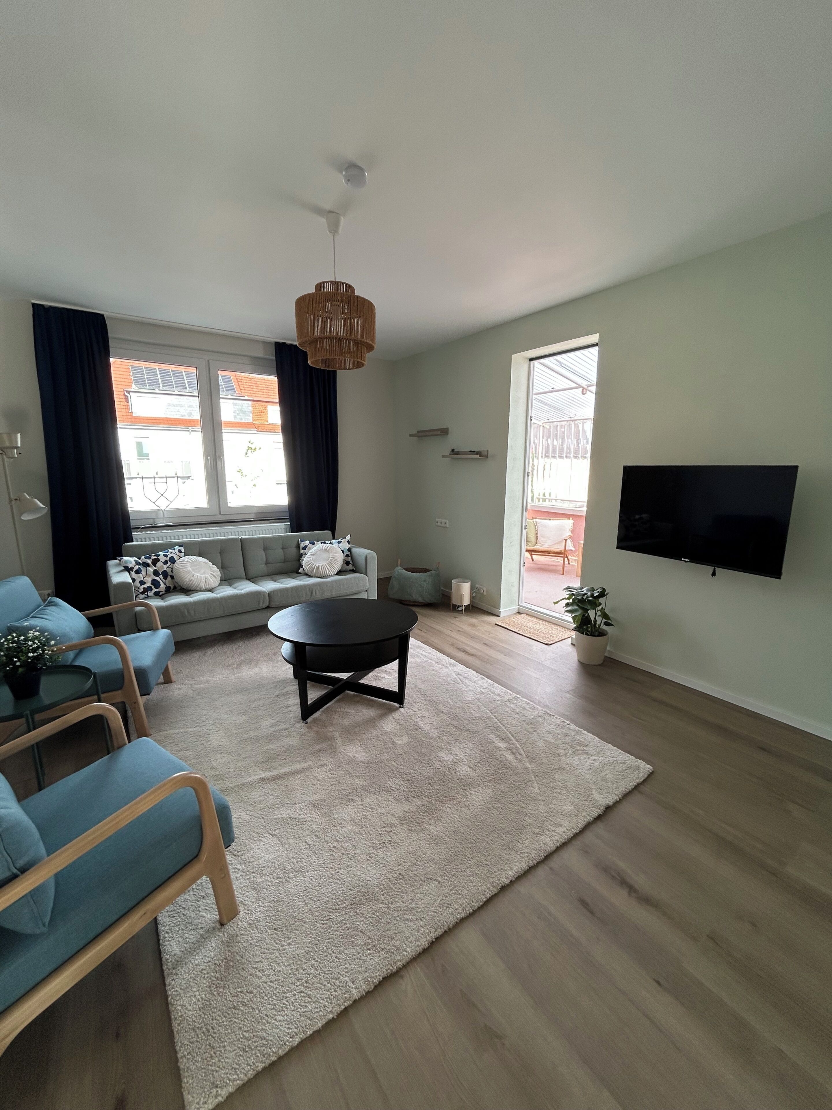 Ein modernes Wohnzimmer mit einer Couch, einem Couchtisch und einem an der Wand befestigten Fernseher.