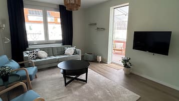 Ein modernes Wohnzimmer mit einer Couch, einem Couchtisch und einem an der Wand befestigten Fernseher.