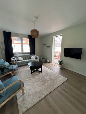 Een moderne woonkamer met een bank, een salontafel en een televisie die aan de muur is bevestigd.