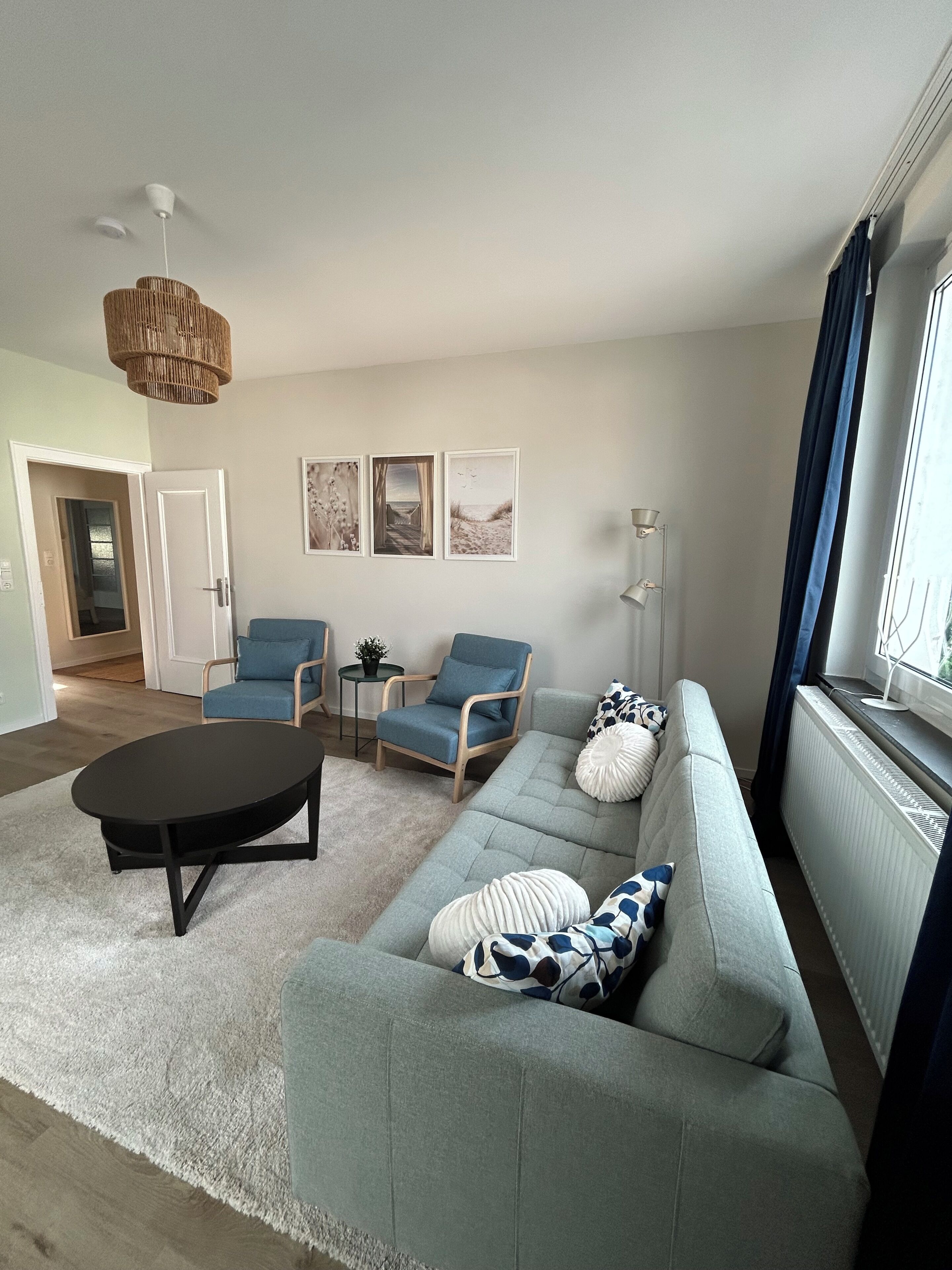 A modern living room with a sofa, two armchairs, a coffee table, and a hanging light fixture.