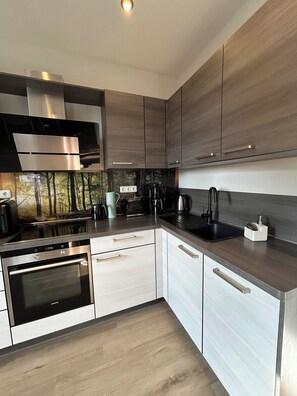 A modern kitchen with stainless steel appliances, wooden cabinets, and a built-in oven.