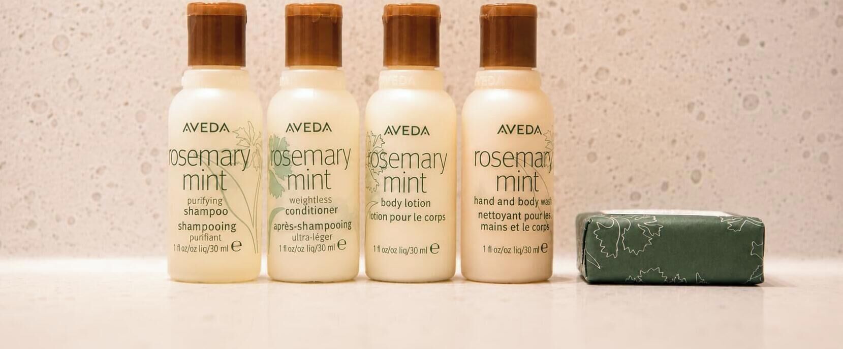 Five bottles of Aveda Rosemary Mint products and a bar of soap.