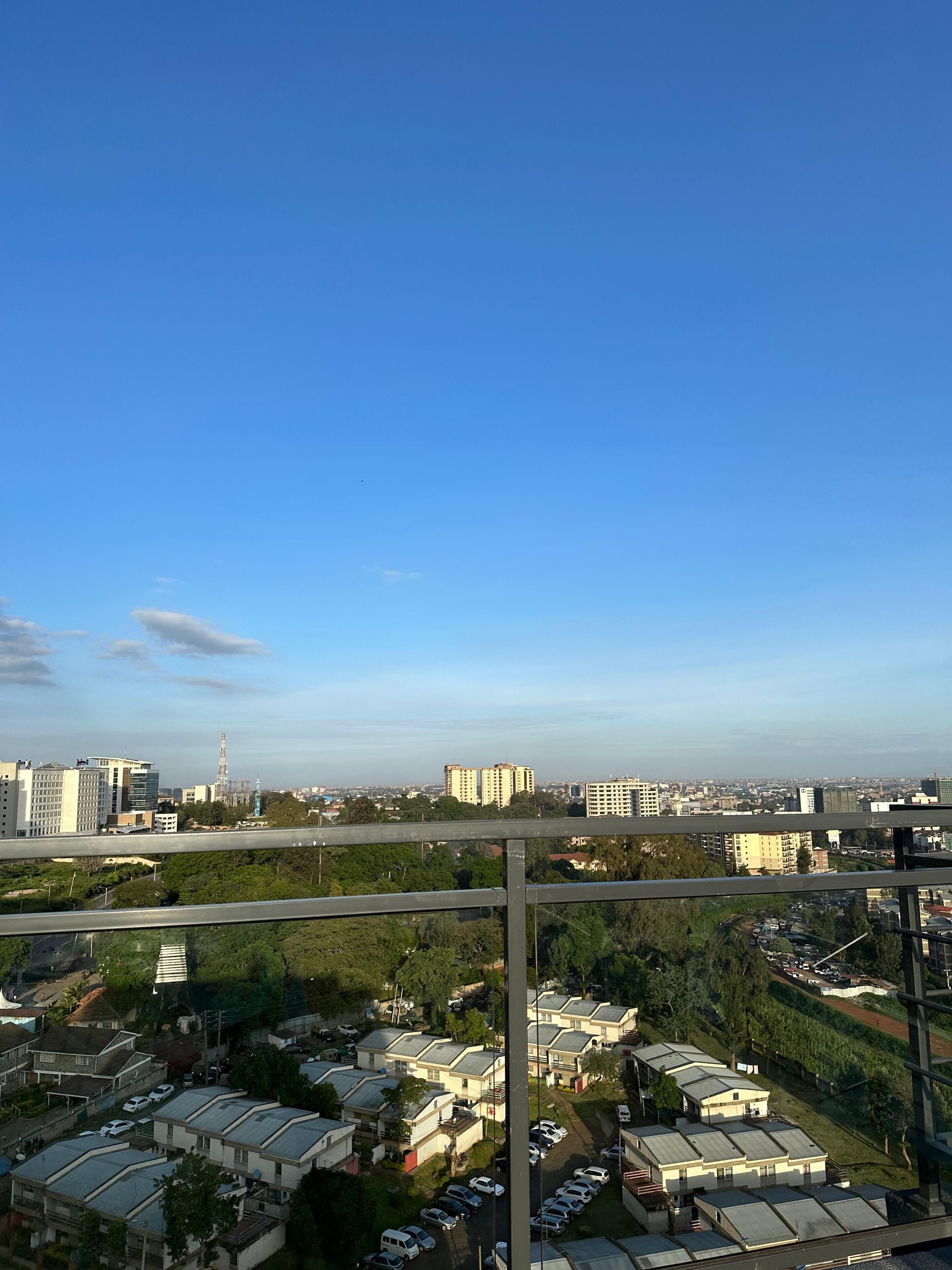 A residential area with multiple-story buildings, a clear sky, and a distant view of a cityscape.