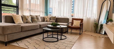 A modern living room with a sectional sofa, a round coffee table, and a leather armchair.