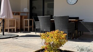 An outdoor seating area with wicker chairs, a wooden table, and a potted plant. - Villa with pool and jacuzzi near Châteauneuf-du-Pape – 9 people (Sorgues)