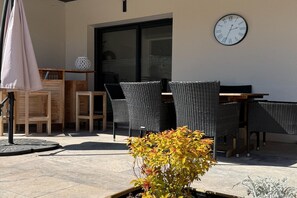 An outdoor seating area with wicker chairs, a wooden table, and a potted plant. - Villa with pool and jacuzzi near Châteauneuf-du-Pape – 9 people (Sorgues)