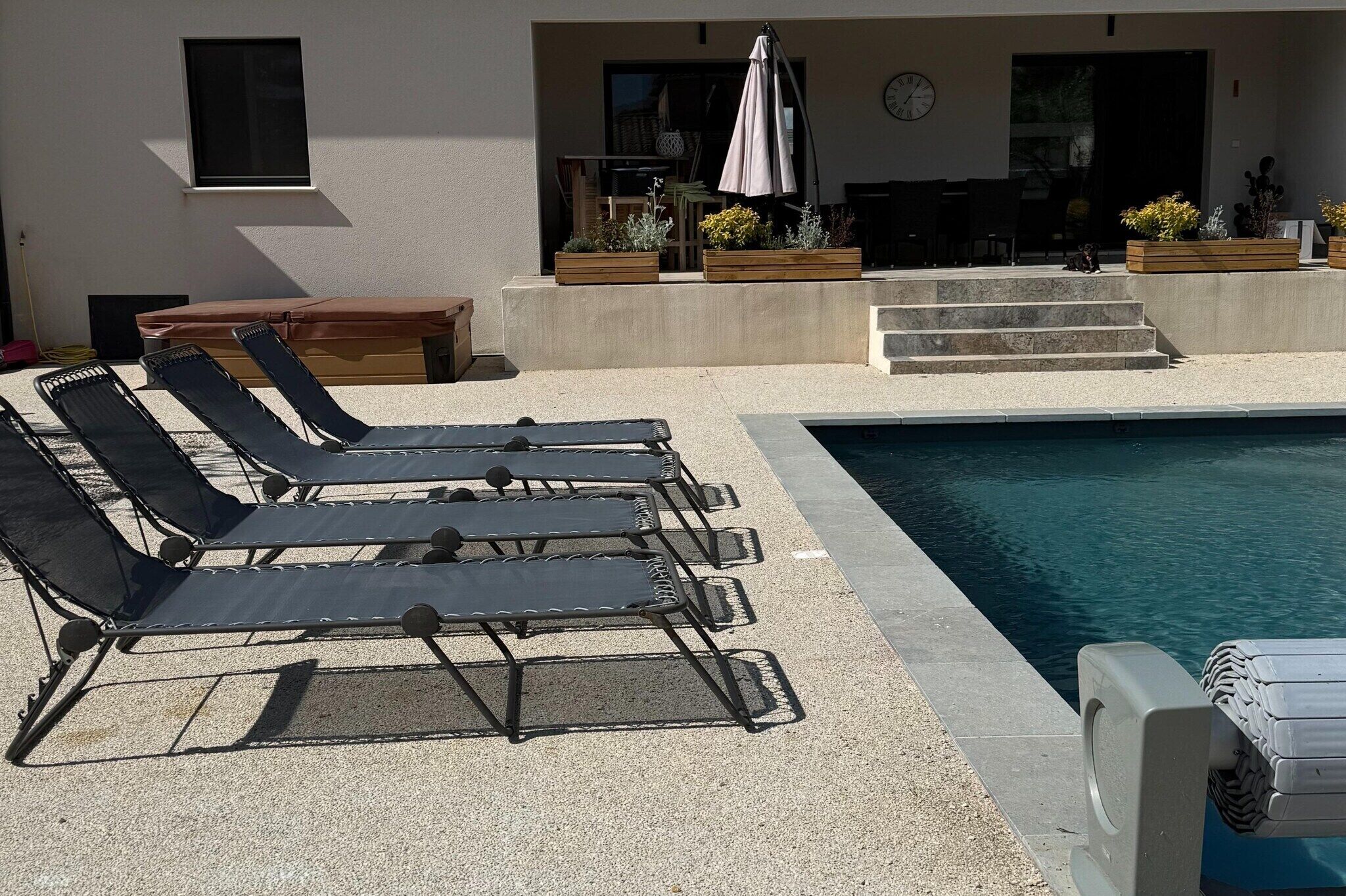 Zona de piscina con sillas de descanso, una pequeña mesa y un espacio de estar con una mesa y sillas.