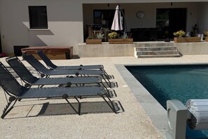 A poolside area with lounge chairs, a small table, and a seating area with a table and chairs. - Villa with pool and jacuzzi near Châteauneuf-du-Pape – 9 people (Sorgues)