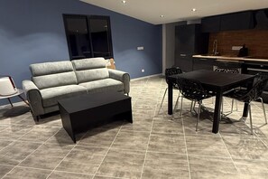 Ein modernes Wohnzimmer mit Sofa, Couchtisch und Essbereich.