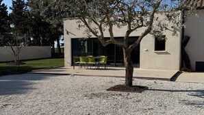 A building with a gravel patio, a tree, and a seating area with chairs. - Villa with pool and jacuzzi near Châteauneuf-du-Pape – 4 people (Sorgues)