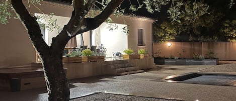 A well-lit outdoor area with a tree, seating, and planters.