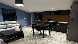 A modern kitchen with a dining area, including a sofa, a coffee table, and a dining table with chairs. - Villa with pool and jacuzzi near Châteauneuf-du-Pape – 4 people (Sorgues)
