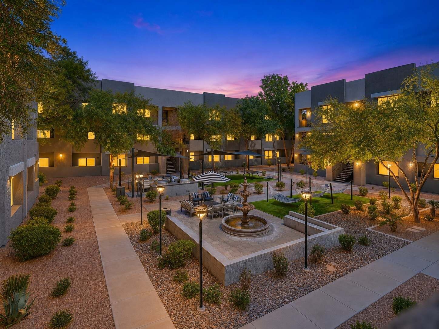 A courtyard with outdoor seating, a fountain, and trees.
